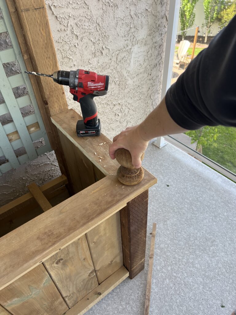 Erin is screwing fence finials into the bottom corners of the planter.