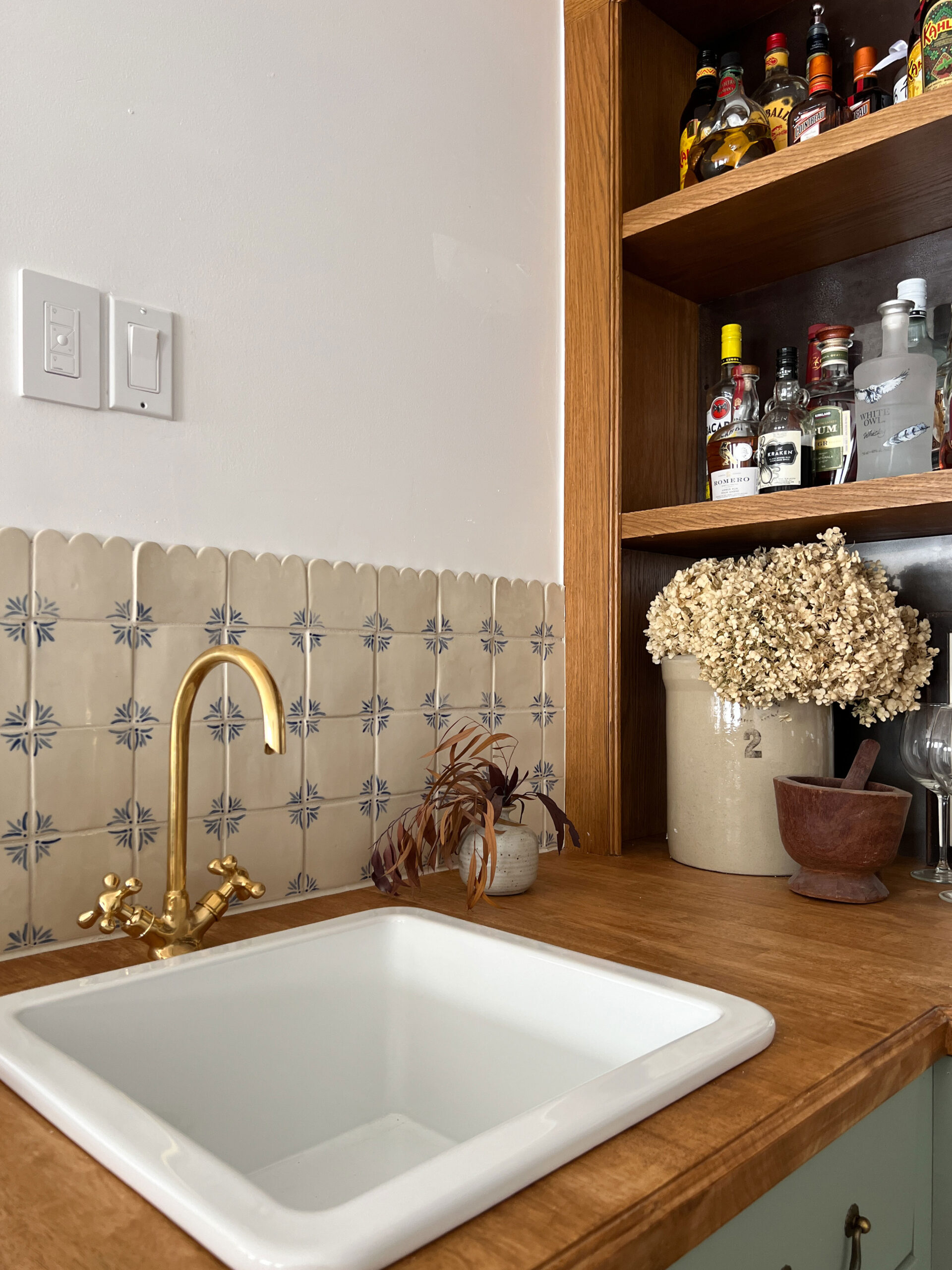 Close up of handmade tile, sink and brass faucet, and wood counters and wood back bar