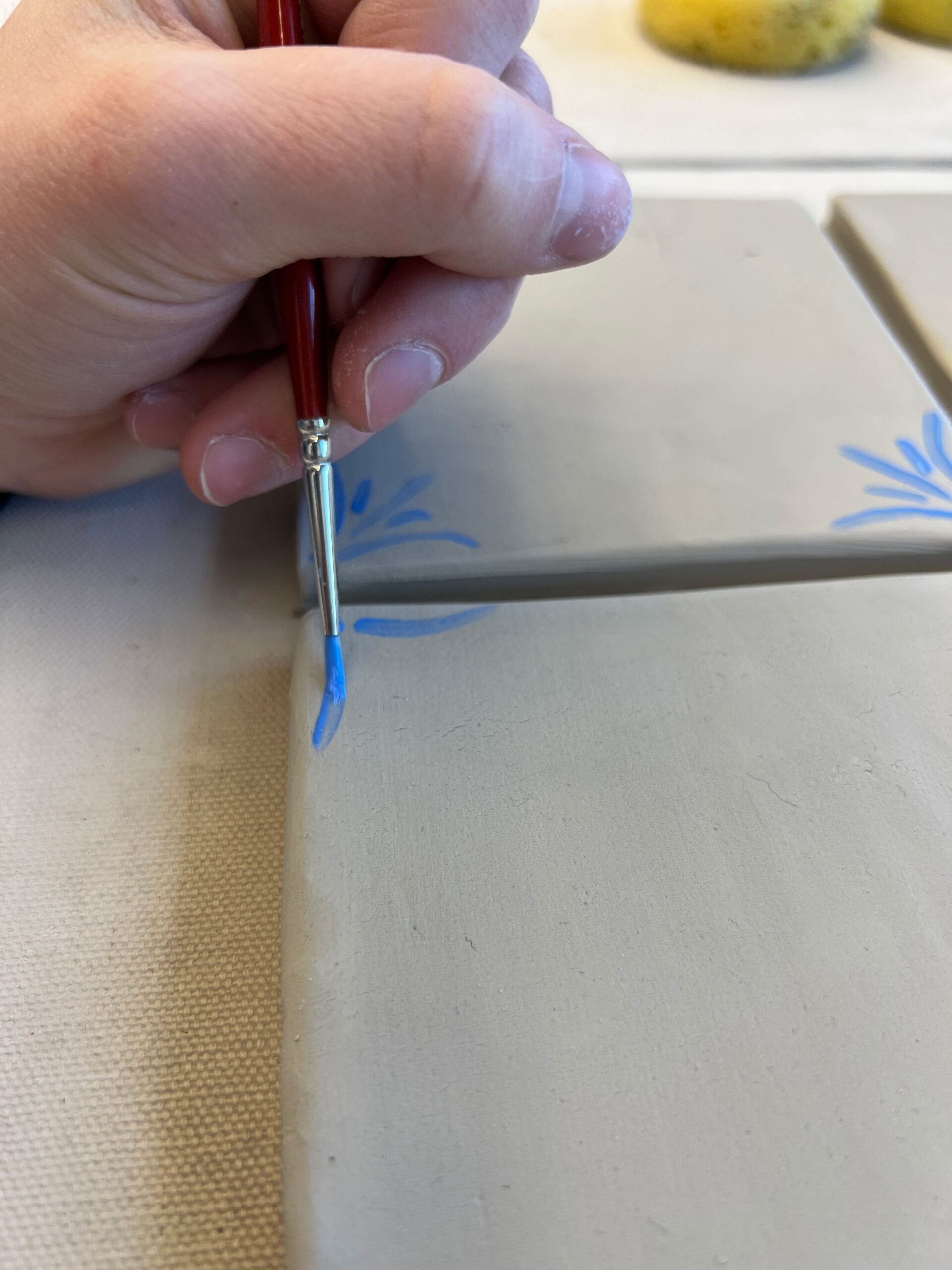 painting blue flowers on corner of tile