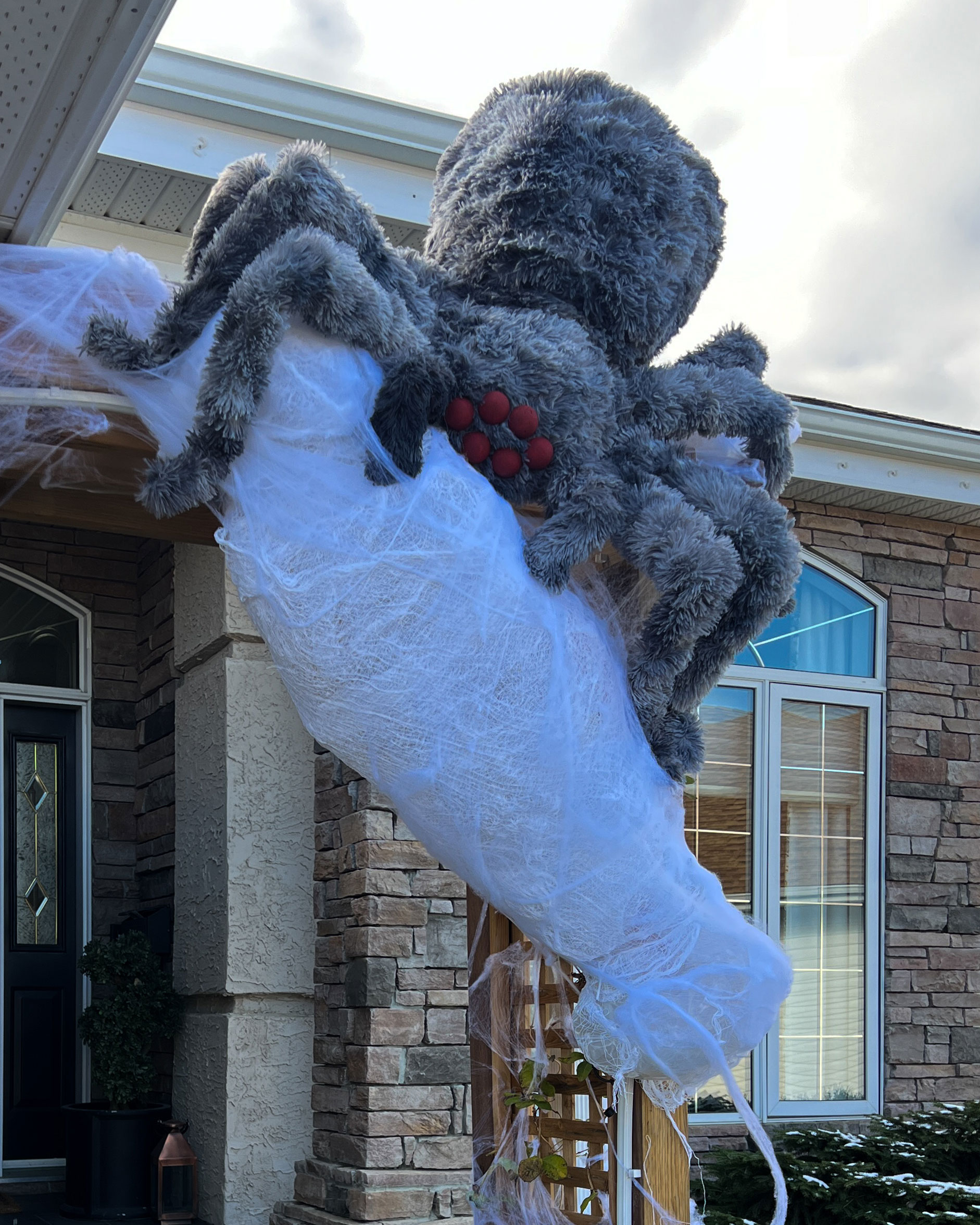 DIY Halloween Spider on a house with a body wrapped in a web
