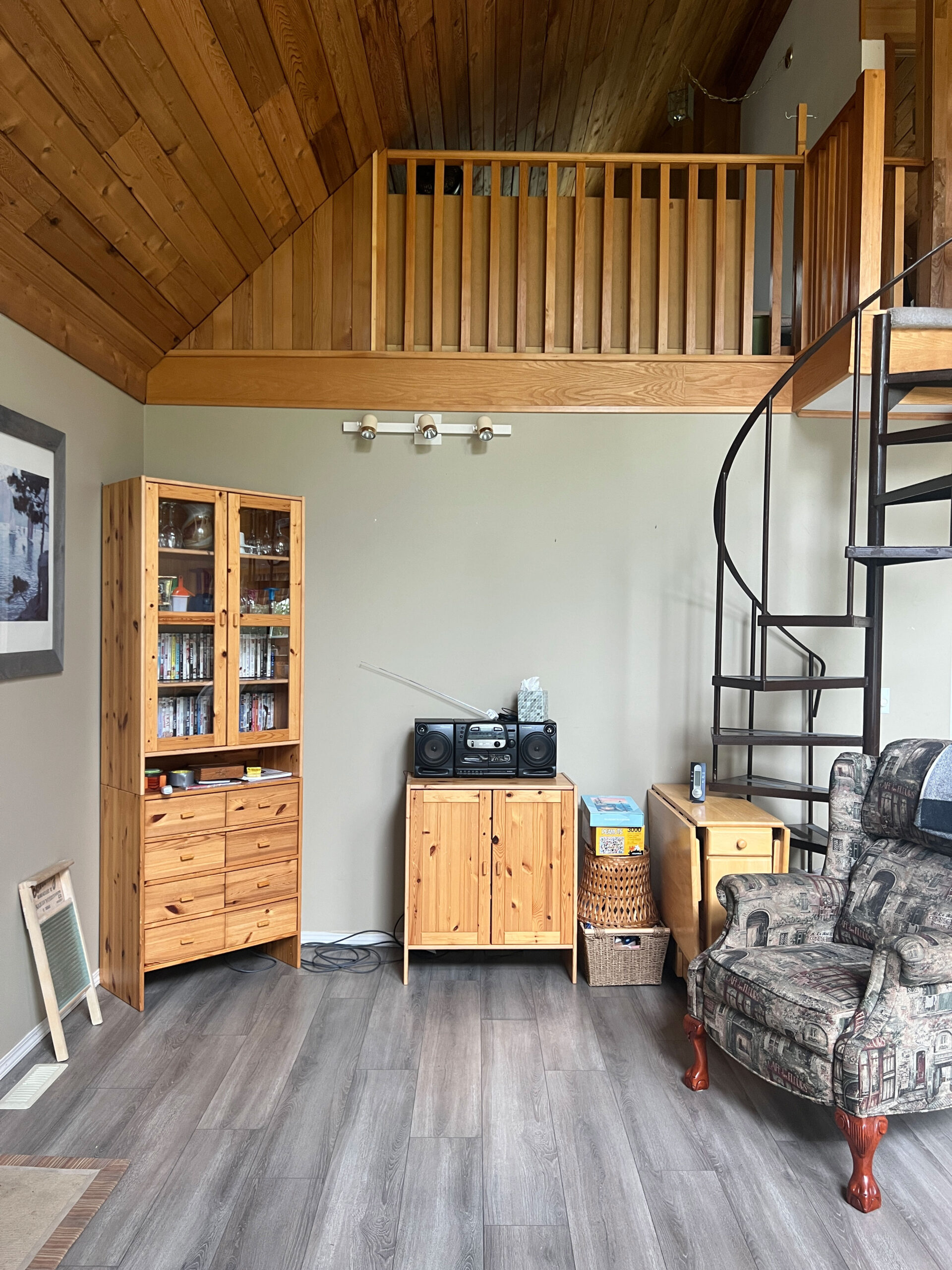 cabin wall with wood ceilings, grey floors, and multiple small furniture pieces