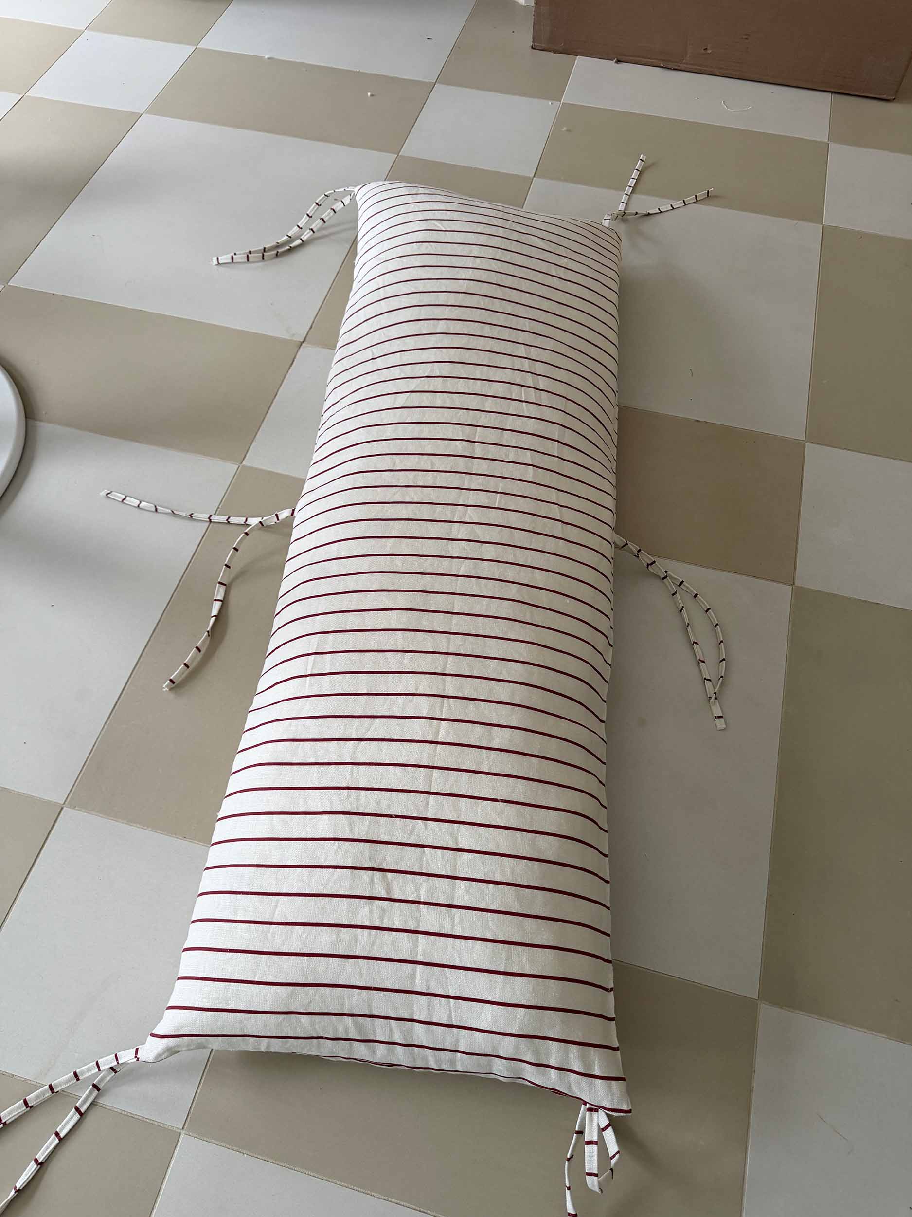 striped headboard pillow laying on a tile floor