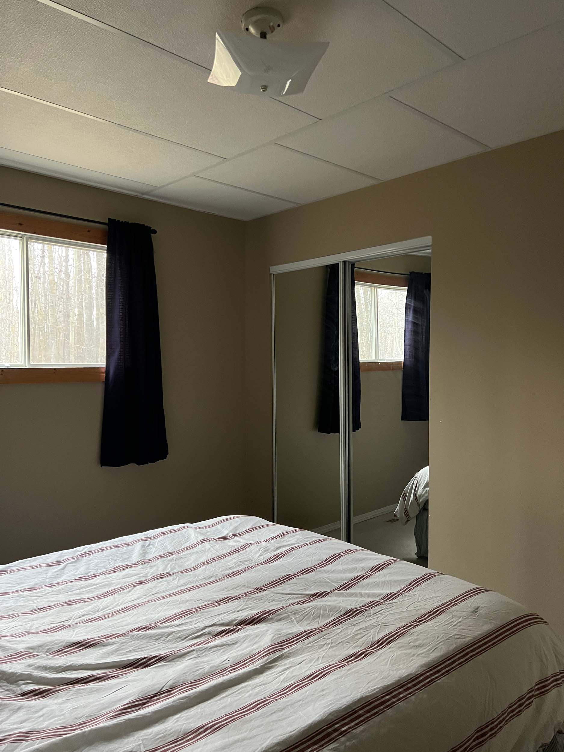 Dark bedroom with mirrored closet doors and small window