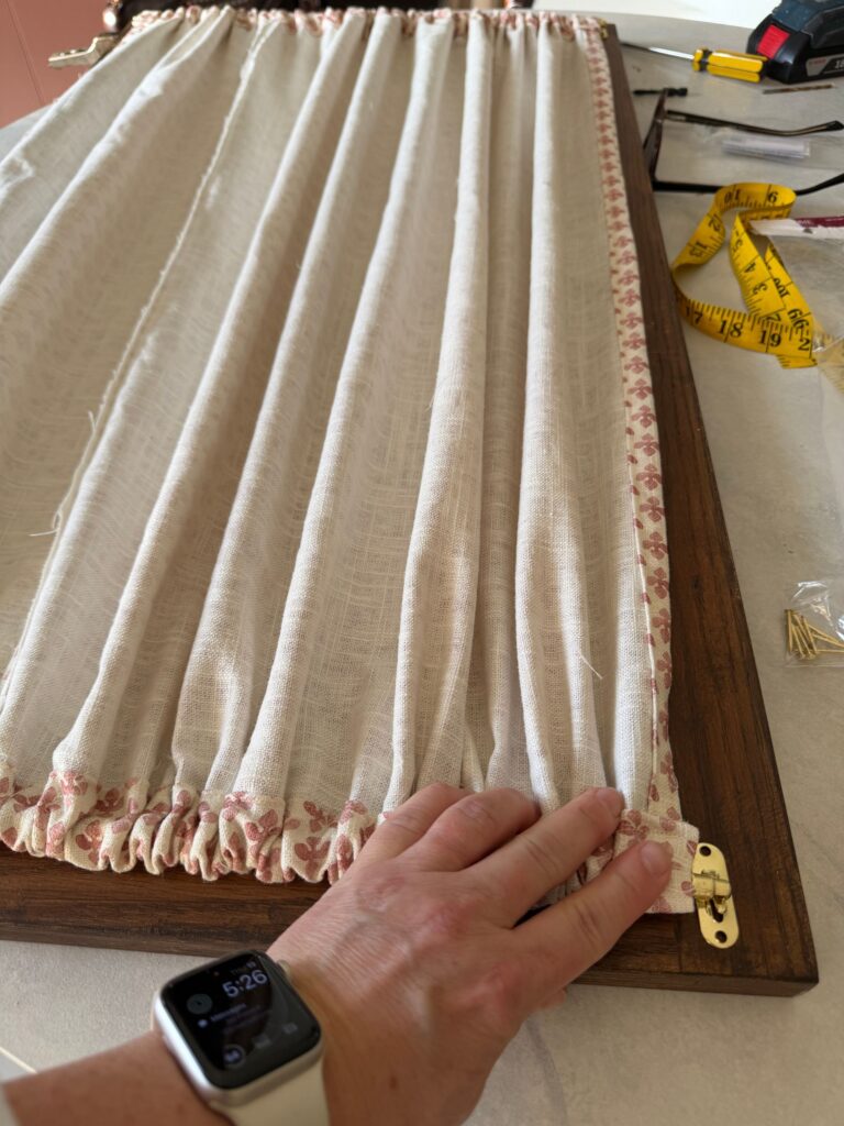 Putting the curtains on the back of the hutch doors.