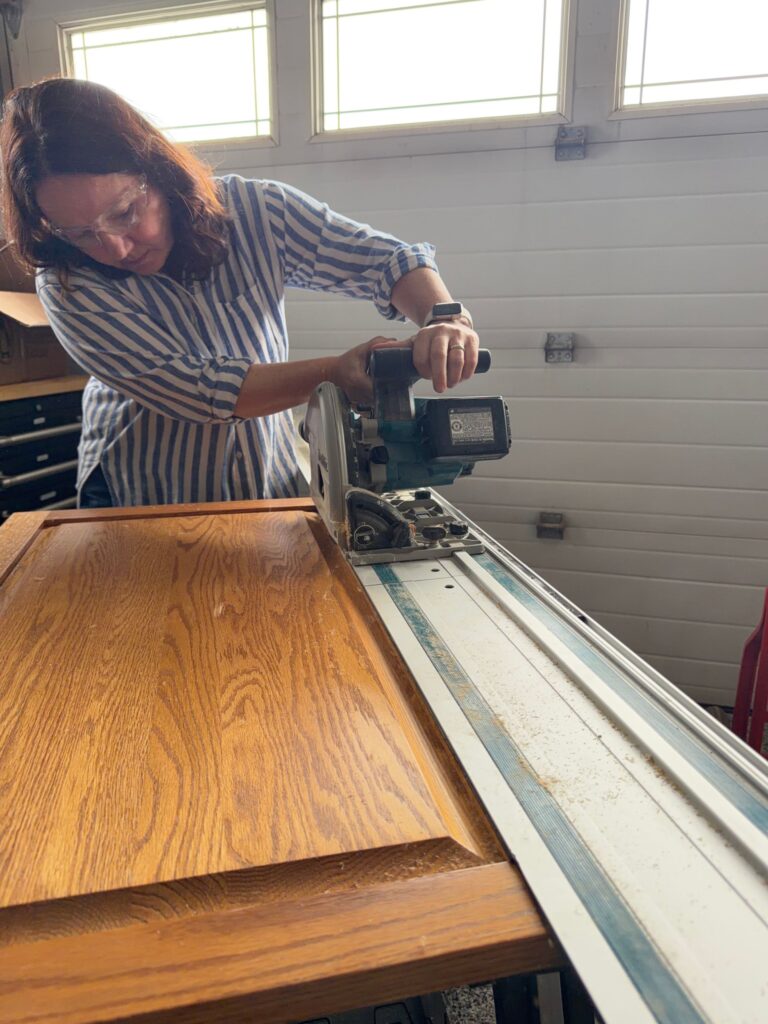 Using a plunge saw to cut a panel out of the cabinet doors.