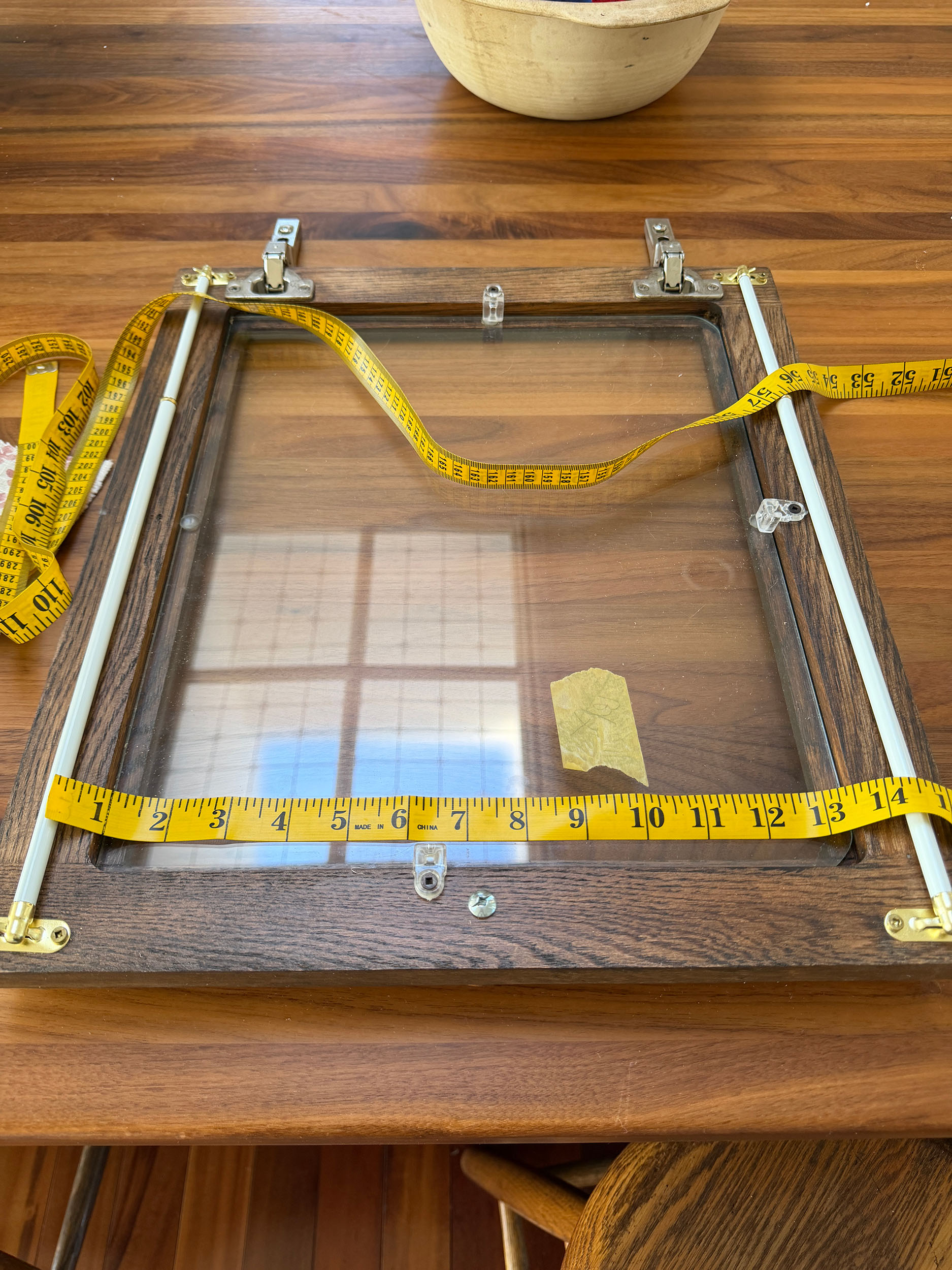 glass door with two sash rods on it with a measuring tape 