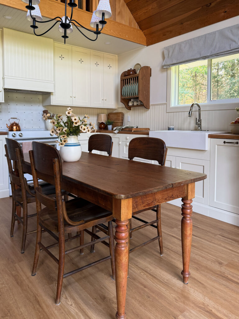 Ikea kitchen with cream coloured cabinets, butcherblock counters, antique table, freestanding wood pantry, plate rack