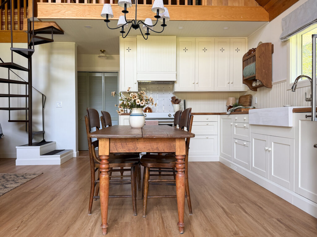 Ikea kitchen with cream coloured cabinets, butcherblock counters, antique table, freestanding wood pantry, plate rack