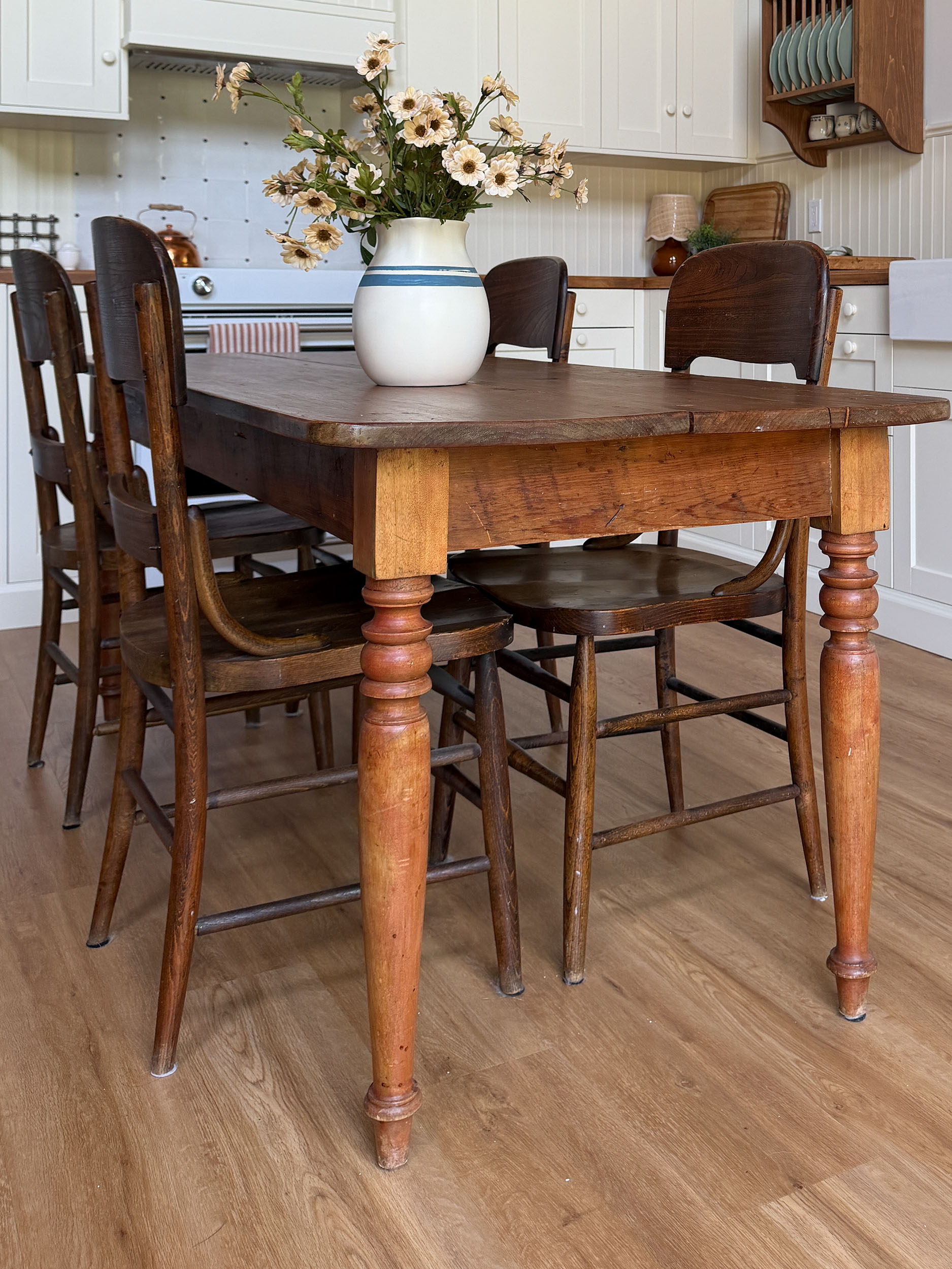 A farmhouse table with antique chairs