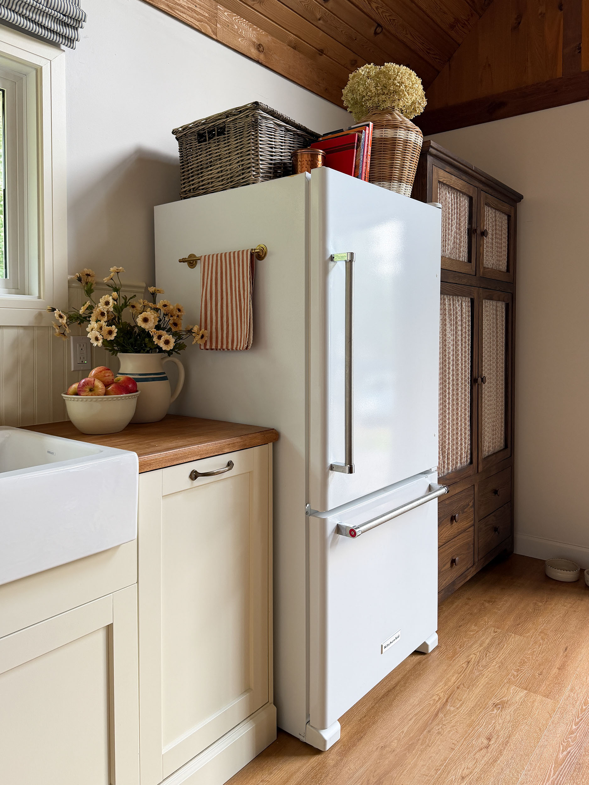Ikea kitchen with cream coloured cabinets, butcherblock counters, antique table, freestanding wood pantry, plate rack