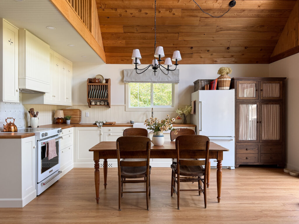 Ikea kitchen with cream coloured cabinets, butcherblock counters, antique table, freestanding wood pantry, plate rack 