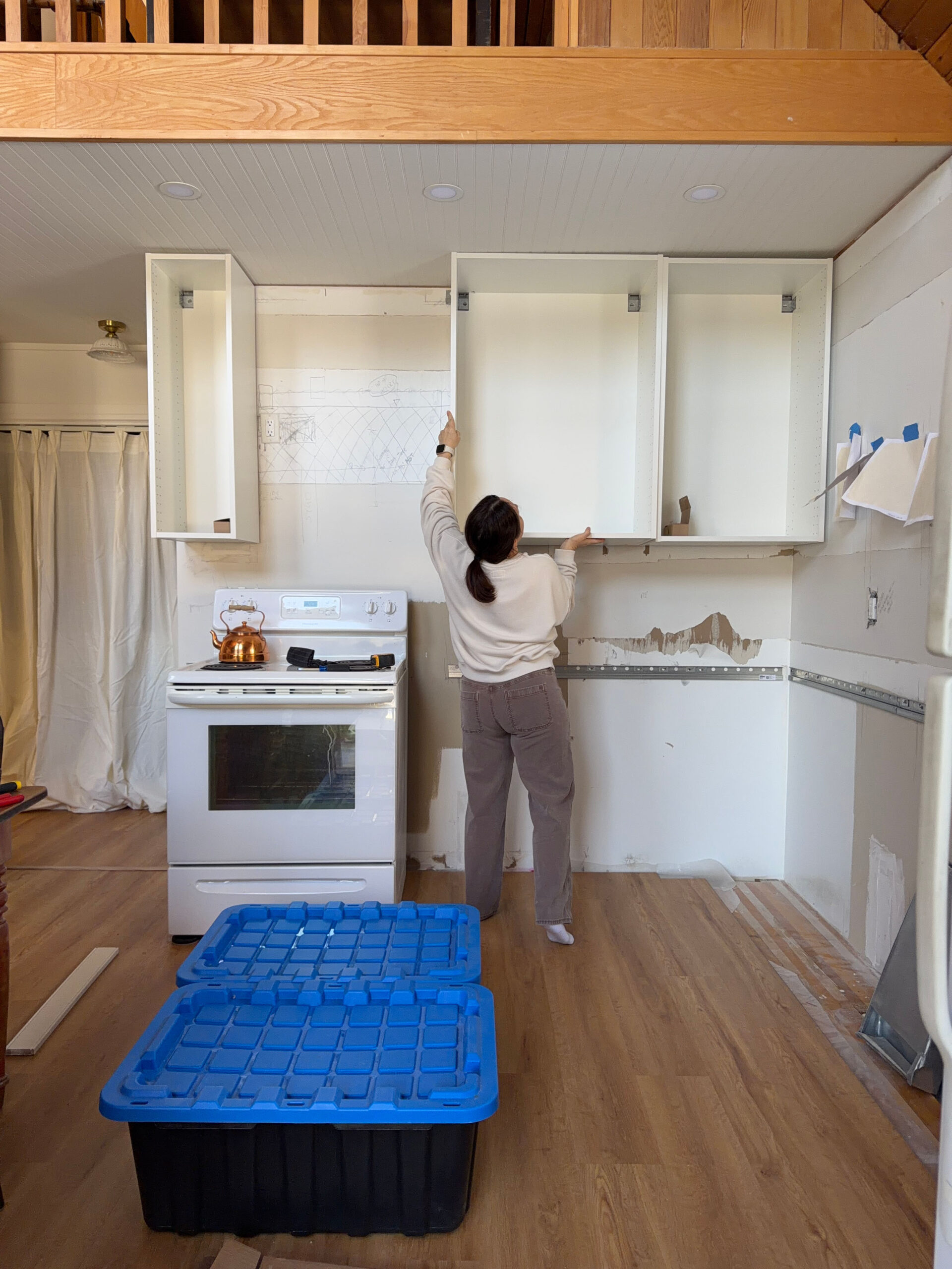 girl lifting an ikea kitchen cabinet onto a wall