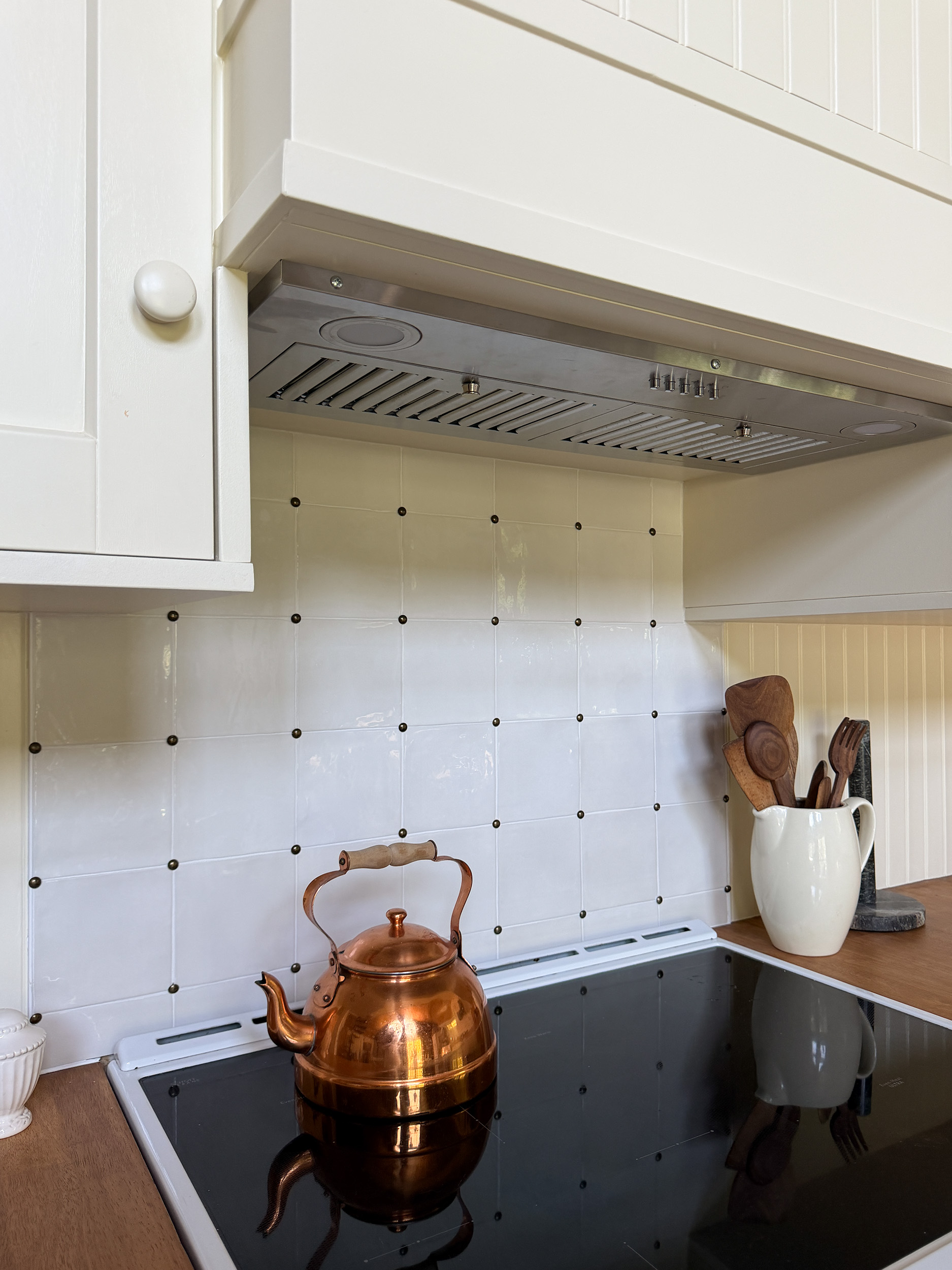 A stove with a white square tile backsplash and pins in the tile corners