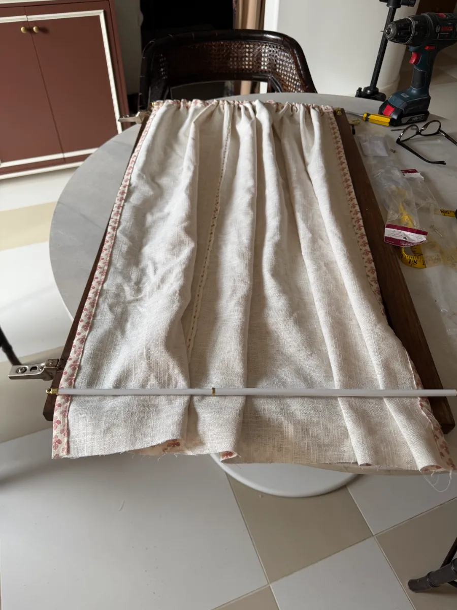 One side of door curtain on a rod and the other side loose, door sitting on table