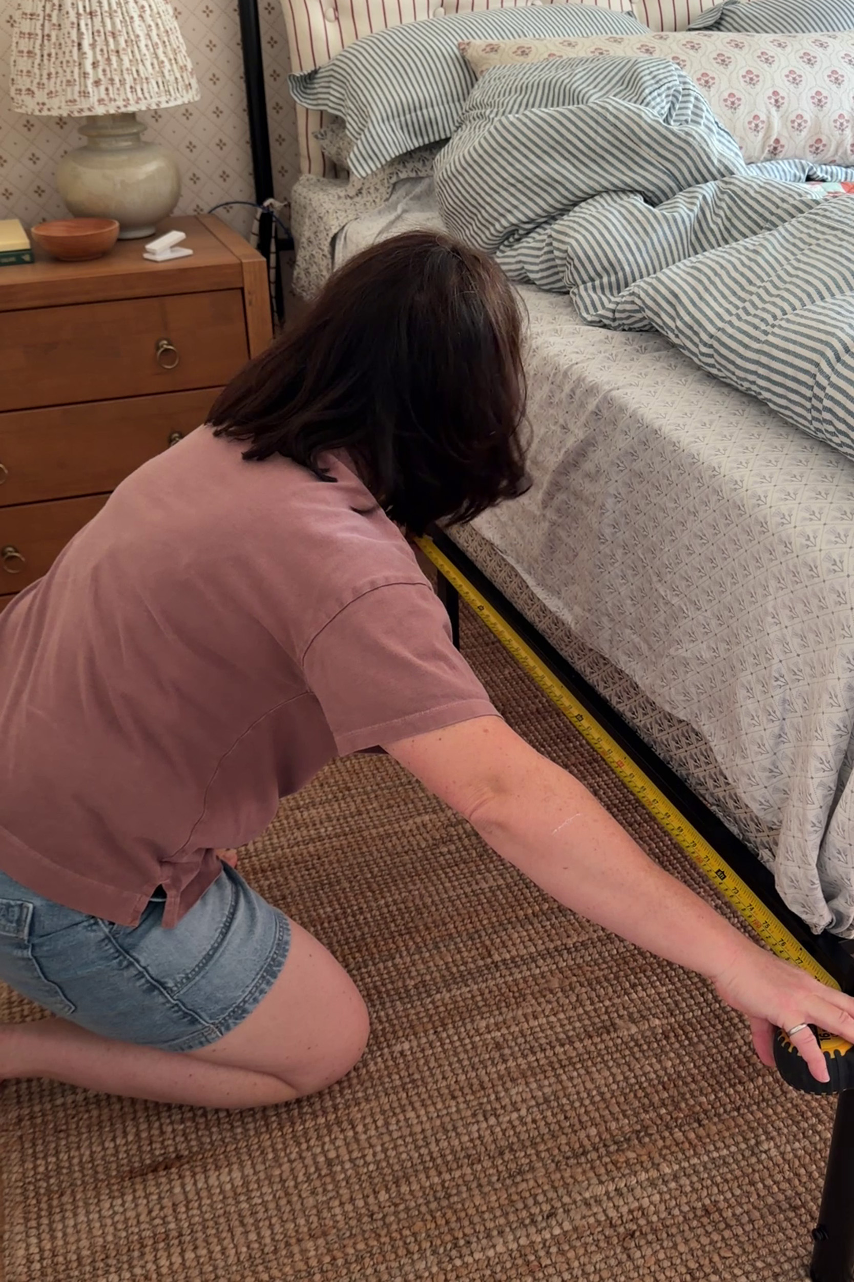 Girl holding measuring tape along length of bed