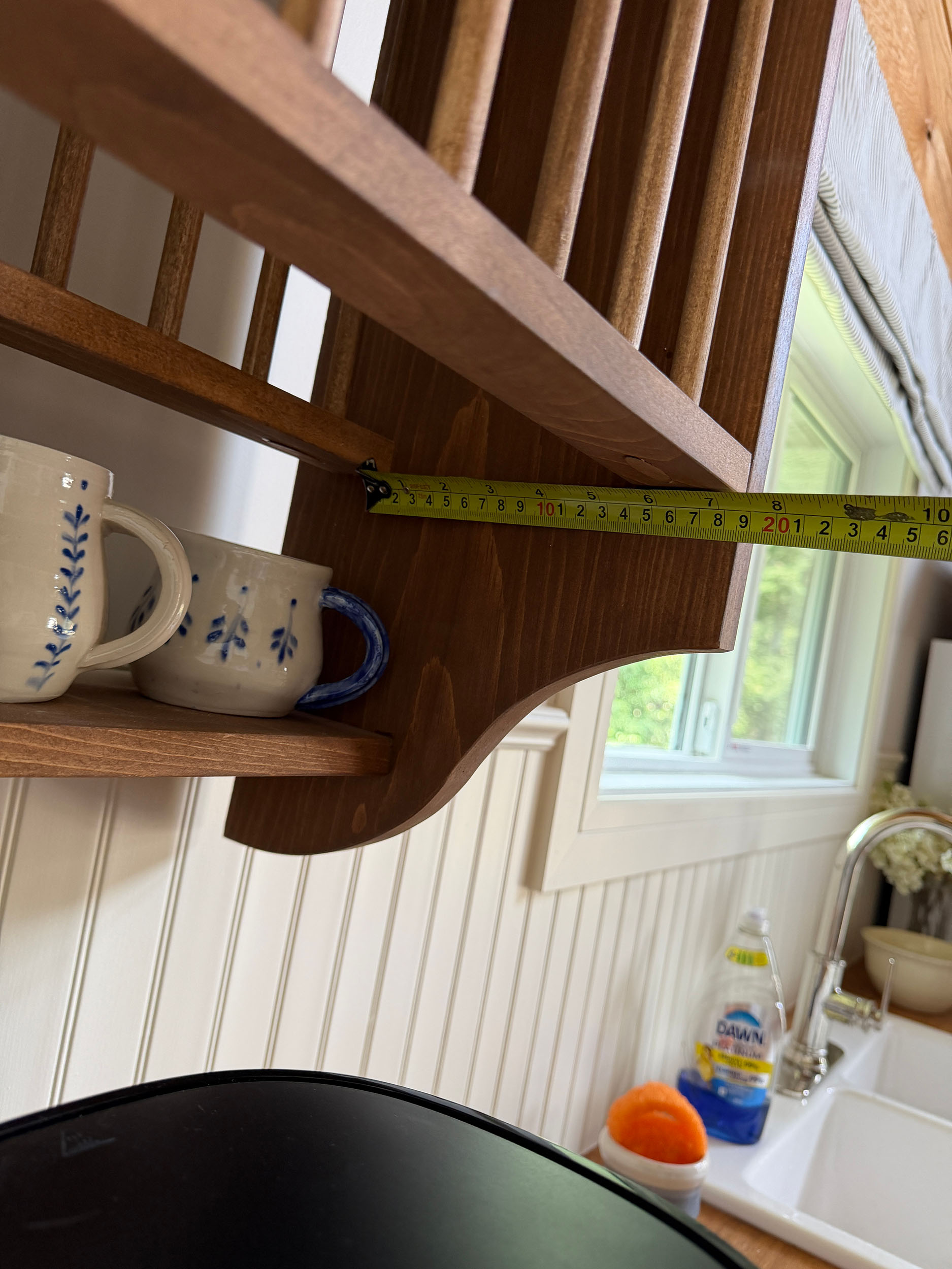 holding measuring tape up along the bottom rails of a diy plate rack